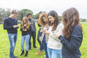 Multiethnic group of friends looking at their own smart phone. Technology, internet and social network addicion concepts, modern social issues.
